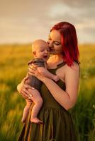 een moeder houdt haar drie maanden oude zoon teder in haar armen in een tarweveld. foto
