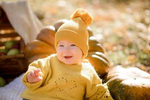 schattig klein meisje zittend op pompoen en spelen in herfstbos foto