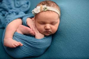 schattig pasgeboren meisje slapen op een blauwe achtergrond in een blauwe verpakking. foto