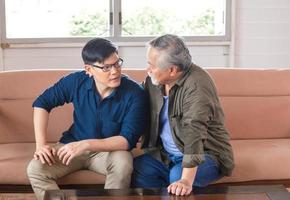 senior aziatische vader geeft advies volwassen zoon in woonkamer, bejaarde man geeft advies aan zijn volwassen zoon, geluk familieconcepten foto