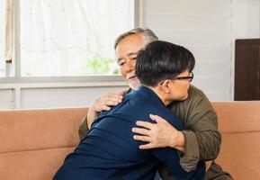 senior aziatische vader geeft advies volwassen zoon in woonkamer, geluk familieconcepten foto