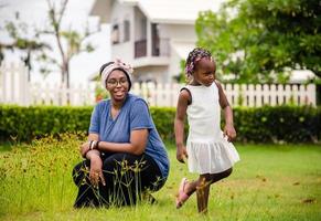 portret van Afro-Amerikaans meisje en moeder die samen buiten spelen, gelukkig familieconcept. foto