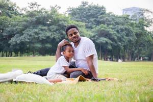 vrolijke afro-amerikaanse vader en zoon spelen in het park, geluksfamilieconcepten, ouder en kind spelen in het park foto
