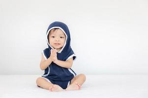 gelukkige babyjongen met blauwe capuchon zittend op bed, kinderen spelen concept foto