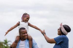 gelukkige vader moeder en dochter spelen samen buiten, vrolijke Afro-Amerikaanse familie genieten in het park, geluk familieconcepten foto