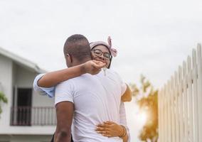 vrolijke afro-amerikaanse vrouw die huissleutels vasthoudt terwijl ze vriendje knuffelt in hun nieuwe huis, geluksfamilieconcepten foto