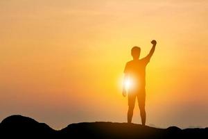 silhouet van man met uitknippad viering succes geluk op een bergtop op strand avondlucht zonsondergang achtergrond, sport en actief leven concept. foto