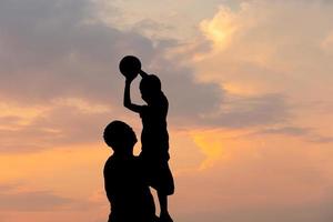 silhouet van vader en zoon met bal avondlucht zonsondergang achtergrond, sport en genieten van het leven concepten. foto