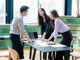 groep jonge zakelijke teamdiscussies iets terwijl ze samen aan de co-working space-tafel zitten, strategie plannen en brainstormen, collega's denken concept foto