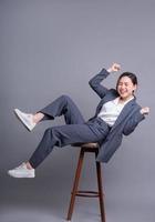 jonge Aziatische zakenvrouw zittend op een stoel en poseren op een grijze achtergrond foto