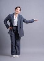 jonge Aziatische zakenvrouw staande op een grijze achtergrond foto