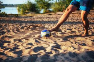 jonge kerel die volleybal speelt op het strand foto