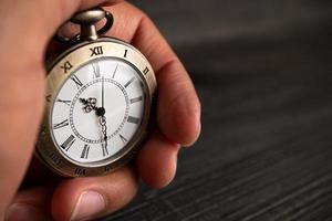 mannen handen houden een zakhorloge en een zwarte achtergrond. foto