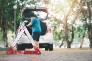 aziatische man vindt gereedschap in de auto voor autoreparatie na een autopech op straat. concept van voertuigmotorprobleem of ongeval en noodhulp van professionele monteur foto