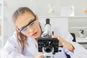 een mooie vrouwelijke wetenschapper is actief in een wetenschappelijk lab met verschillende apparatuur in het lab. foto