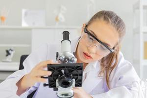 een mooie vrouwelijke wetenschapper is actief in een wetenschappelijk lab met verschillende apparatuur in het lab. foto