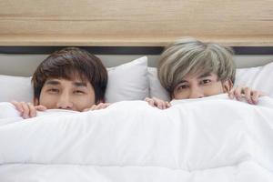 een mannelijk stel met een aziatische man slaapt samen in een bed, een symbool van seksuele diversiteit, dat uiting geeft aan openlijk homoseksuele mannen die lgbt-concepten accepteren. foto