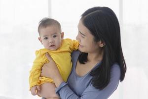 een Aziatische moeder draagt haar baby met liefde en zorg. foto