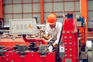 fabrieksarbeider die het elektrische machineproces controleert op een industriële werkplek, met een veiligheidshelm op foto