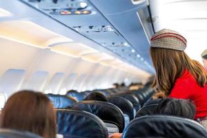 stewardess in rode uniformdiensten en controles voor alles correct rondom de passagiersstoel foto