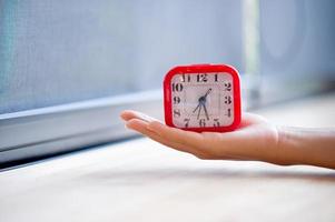hand en rode wekker die elke ochtend het alarm laat zien, het concept van stiptheid foto