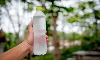 een hand en een flesje drinkwater voor een marathonatleet foto