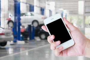 smartphone in de hand met autobandenreparatiediensten wazige achtergrond foto