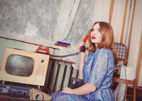 portret van ouderwetse vrouw in ussr-stijl die aan de oude telefoon in retro interieur praat foto