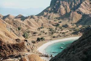 uitzicht op de savanne heuvels op padar eiland met kust en boot foto