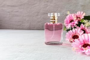 roze parfumflesje met roze bloemen foto