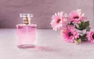 roze parfumflesje met roze bloemen foto