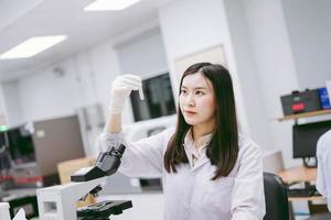 jonge vrouwelijke medische wetenschapper die reageerbuis in medisch laboratorium bekijkt foto