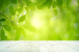 verse groene bladeren natuur met bokeh op lege houten tafel achtergrond foto