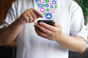 man die een mobiele telefoon gebruikt voor communicatie via sociale media met een symbool van like, share, love. foto