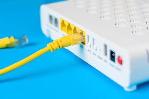 internetmodem router hub met een kabel die op blauwe achtergrond aansluit foto