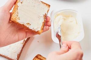 vrouw maakt met de hand sandwich, geroosterd brood met kaas foto