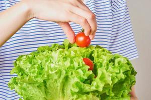 vrouw houdt boeket sla met cherrytomaat in handen. gezond voedingsconcept foto