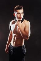 sexy jonge man met een naakte torso op donkere achtergrond. foto