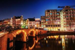 kanaal in amsterdam bij nacht. gebouwen en straten markeren foto