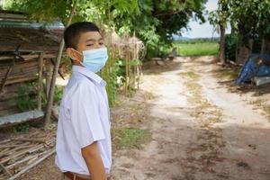 mannelijke student die een antivirusmasker draagt dat naar school gaat, het coronavirus voorkomt foto