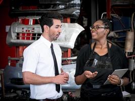 afrikaanse verkoopster beveelt auto-reserveonderdelen aan voor een klant vanaf een tabletcomputer in auto-onderdelen in magazijnen. foto