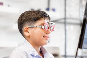 portret van een kind met een oogtestbril in de optische winkel, glimlachende Indisch-Thaise jongen die een bril kiest in de optiekwinkel foto