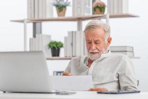 bezorgde senior man die hun rekeningen controleert, gepensioneerde bejaarde oude familie die documenten leest, volwassen man in woonkamer met laptop foto