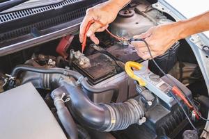 automonteur bezig met automotor controleren batterij in mechanica garage, reparatie en onderhoudsservice foto