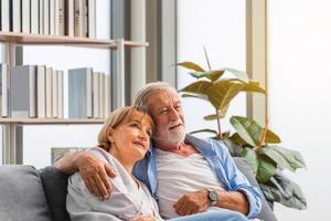 gelukkig senior paar in woonkamer, oudere vrouw en een man ontspannen op een gezellige bank thuis, gelukkige familieconcepten foto