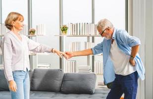 portret van een gelukkig senior koppel dat danst in de woonkamer, een oudere vrouw en een man die danst, gelukkige familieconcepten foto