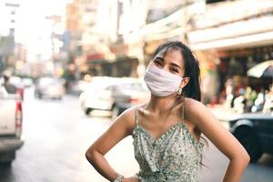 gelukkige aziatische volwassen vrouw tan huid draag masker op gezicht voor nieuw normaal. foto