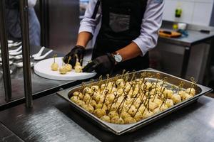 een kok in zwarte handschoenen bereidt kaasballetjes voor. foto