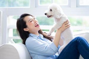 jonge aziatische vrouw die thuis met hond speelt foto