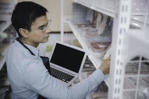 zakenman, eigenaar, personeel, gebruik, computer, laptop, controleren, product, inventaris, plank, in, supermarkt foto